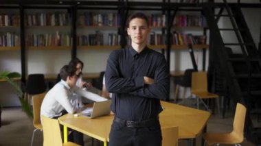 Beyaz kütüphanecinin kameraya kamerayla kamera yada bir portresi kitaplıklarda göğüs üzerinde el ele tutuşuyor.