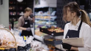 Siyah önlüklü ve eldivenli bir kadın bir markette mal envanterini çıkarır..