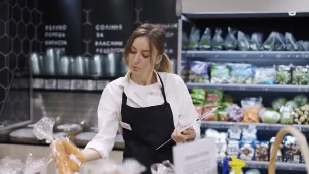 一位穿着黑色围裙和手套的女工在杂货店里清点商品 — 图库视频影像