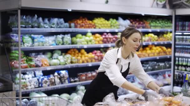 穿着黑色围裙和手套的女工在超市里为水果长袜 年轻的员工在工作 — 图库视频影像