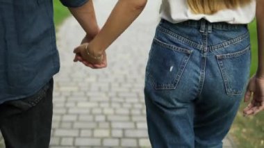 Genç pozitif bir çift el ele yürür, bir yaz parkında tanışırlar. Kız ve oğlan sarışınlar. İyi yürüyüşler. Arka plan.