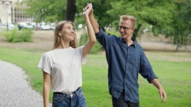 Genç pozitif bir çift el ele yürür, bir yaz parkında tanışırlar. Kız ve oğlan sarışınlar. İyi yürüyüşler. Arka plan.
