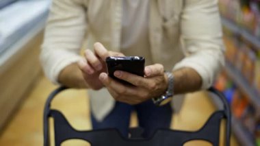 Orta yaşlı bir adam dükkana giriyor, bir el arabası taşıyor ve elinde bir telefon tutuyor. makro fotoğrafçılık.
