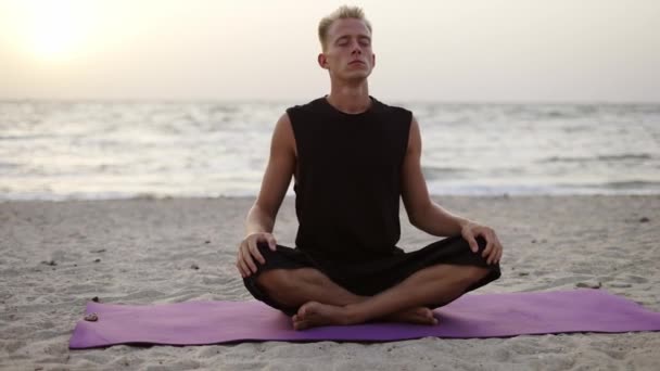 若い男が太陽の夜明けの間に座っている間 ヨガやスポーツマットで瞑想をしています 特定の練習をする レクリエーション — ストック動画