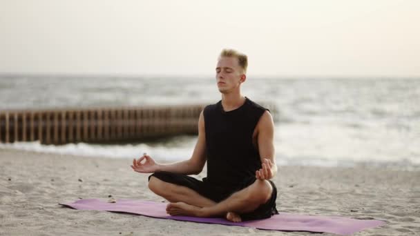 若い男が太陽の夜明けの間に座っている間 ヨガやスポーツマットで瞑想をしています 特定の練習をする レクリエーション — ストック動画