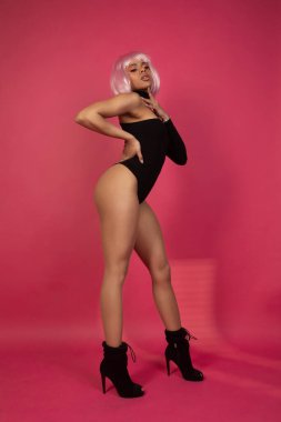 Pembe arka planda pembe saçlı seksi Afro-Amerikalı kadın.