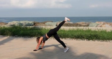 Atletik kadın gün batımı plajında antrenman yapıyor. Aerobik yapan kadın sporcu. Deniz kenarında sağlıklı bir yaşam sürüyor..