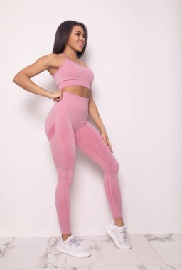 Stüdyoda pembe spor kıyafetleri içinde gülümseyen Afro-Amerikan kadınlarının tam boy görüntüsü.