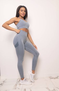 Çekici, yakışıklı, Afro-Amerikan kadın spor kıyafetleri içinde kameraya gülümseyen ve stüdyoda poz veren.