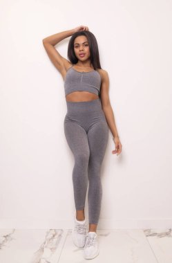 Çekici, yakışıklı, Afro-Amerikan kadın spor kıyafetleri içinde kameraya gülümseyen ve stüdyoda poz veren.