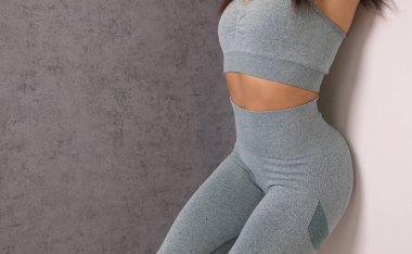 Stüdyoda spor kıyafetli çekici bir kadının orta bölümü.