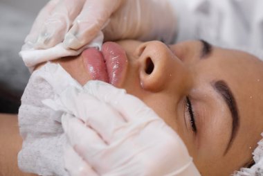 Kozmetik uzmanı, müşterinin cildini geliştirmek için yüz yüzeyine krem özü vitaminleri uyguluyor. Güzellik uzmanı hasta için güzellik tedavisi yapıyor. Sağlık, cilt bakımı, estetik tıp konsepti.