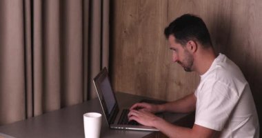 Masaj yapan ve evde dizüstü bilgisayar kullanan genç adamın yan görüntüsü