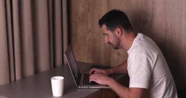 Evde dizüstü bilgisayar kullanan ve boynu ağrıyan genç bir adamın yan görüntüsü