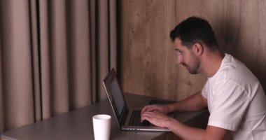 Gece evde dizüstü bilgisayarla çalışırken gözlerini ovuşturan yorgun genç adamın yan görüntüsü