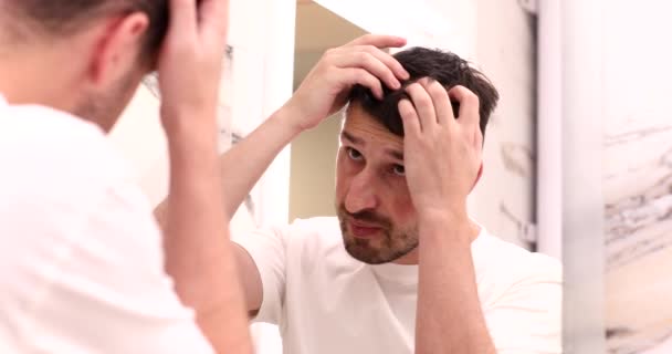 Młody Człowiek Sprawdzając Włosy Patrząc Lustro Łazience — Wideo stockowe