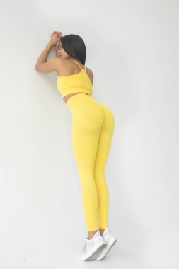 Sarı spor kıyafetli Afro-Amerikan kadının stüdyoda poz verişi.   