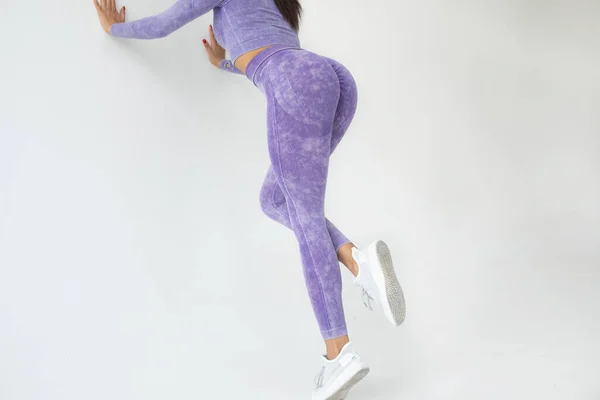 穿紫色运动服的年轻健康女子灰色背景训练的剪影 — 图库照片