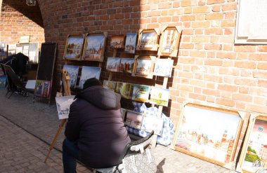 Polonya, Varşova, 12 Mart 2022. Polonyalı adam, Varşova Barbican 'daki gösteriş ve satış direği insanları ve yabancı gezginler için suluboya resim çiziyor.