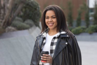 Genç Afrikalı Amerikalı kadın sokakta kahve içiyor..