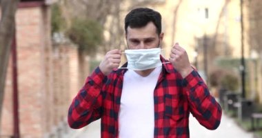 Sokakta tek başına duran ve yüzüne maske takan genç bir adam virüs salgını sırasında yaşıyor..