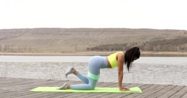 Kalçasında lastik spor kemeri olan fitness antrenörü gölde dururken hamle yapıyor. Siyah kadın fitness.