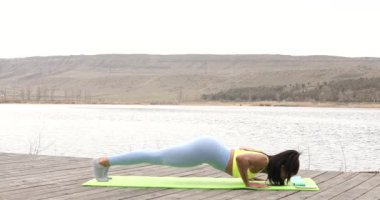 Sportif kadın spor yaparken dışarıda şınav çekiyor. 