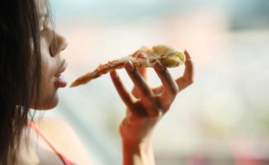 Jambonlu ve peynirli pizza yiyen kadın. 