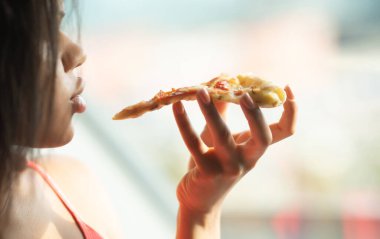 Jambonlu ve peynirli pizza yiyen kadın. 