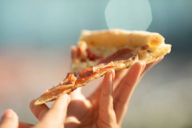 Elinde bir dilim pizza tutan birinin yakın plan fotoğrafı.