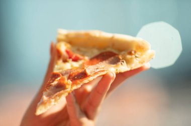 Elinde bir dilim pizza tutan birinin yakın plan fotoğrafı.