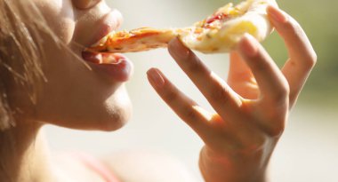 Jambonlu ve peynirli pizza yiyen kadın. 