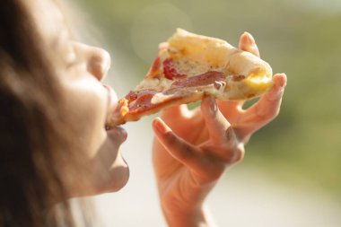 woman eating pizza with ham and cheese 