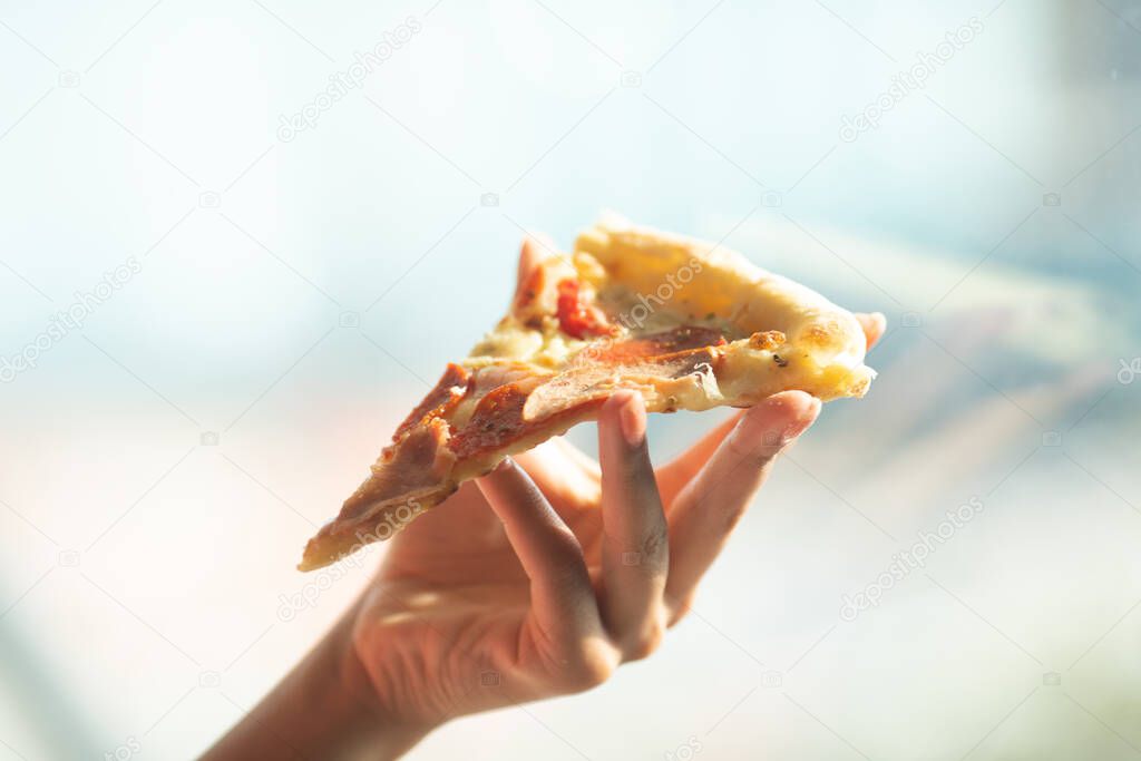 close-up of a person holding a slice of pizza
