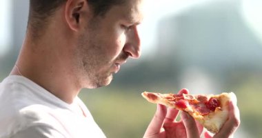 Pizzayı koklayan bir adamın yakın görüntüsü. 