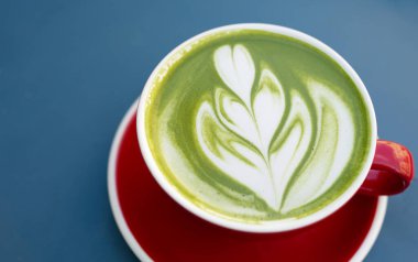 Siyah masada yeşil latte sanatıyla kırmızı kahve. Üst Manzara. Metin için yer.