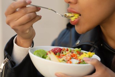 Sebzeli salata yiyen bir kadının yakın çekimi.