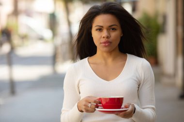 Genç ve güzel bir kadın dışarıda kahve içiyor.