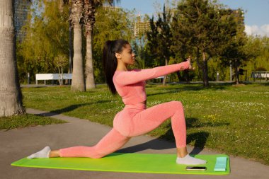 Pembe taytlı güzel siyah bir kadın ve şehir parkında yoga yapan bir kadın..
