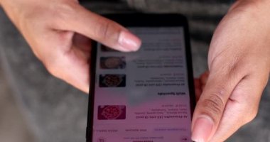 Batumi, Georgia - May 10 2022: Orders Pizza Using Online Delivery. Woman Orders Food Home In Online Store Using a Smartphone. Female Ordering pizza using food delivery app.