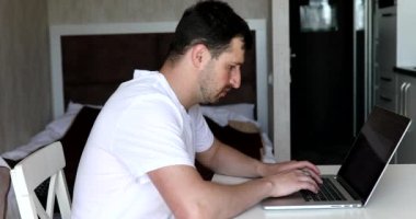 Dizüstü bilgisayarda yazan genç adam, internette çalışan, bilgisayar teknolojisi kullanan profesyonel kullanıcı, ofiste online iş yapan ya da internet sitesinde oturanlar..