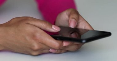 Yan görüş. Evdeki oturma odasında akıllı telefon kullanan ve mesaj yazan bir kız. Genç kadınların yakın plan fotoğrafları..