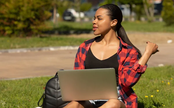 Dışarıda Dizüstü Bilgisayarı Olan Neşeli Afro Amerikan Öğrenci Bilgisayarla Çimenlerde — Stok fotoğraf