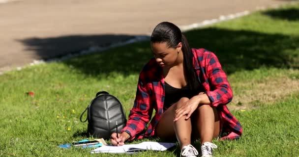 Parktaki Çimenlerde Otururken Elinde Kitap Yazan Neşeli Genç Bir Kadın — Stok video