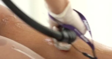 Bir güzellik salonundaki kanepede uzanmış ince bacaklarda lazer tüyü temizliği yapan siyahi kadın. Kozmetik, epilasyon ve spa konsepti. Vücut bakımı. Saç çıkarma prosedürü.