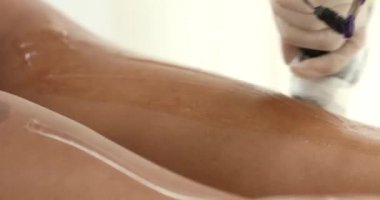 Bir güzellik salonundaki kanepede uzanmış ince bacaklarda lazer tüyü temizliği yapan siyahi kadın. Kozmetik, epilasyon ve spa konsepti. Vücut bakımı. Saç çıkarma prosedürü.