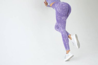 young fit african american woman in purple sportswear posing on grey background 