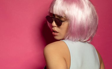 Pembe arka planda pembe saçlı güzel ve seksi bir kadın.