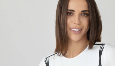 Beyaz arka planda kameraya bakıp gülümseyen güzel, neşeli bir kızın portresi..