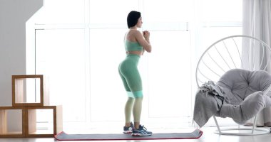 Spor kıyafetli genç bir kadın oturma odasında elastik bantla spor aerobik egzersizleri yapıyor. Ev sağlığı ve sağlık konsepti.